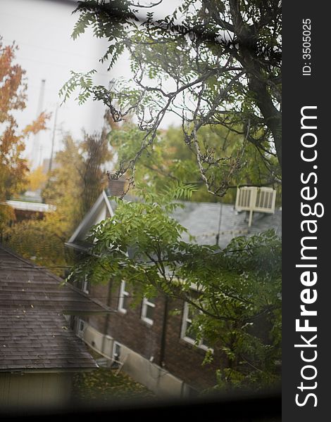 Through the panes of a window, two houses made of brick located side by side in autumn surroundings. Through the panes of a window, two houses made of brick located side by side in autumn surroundings