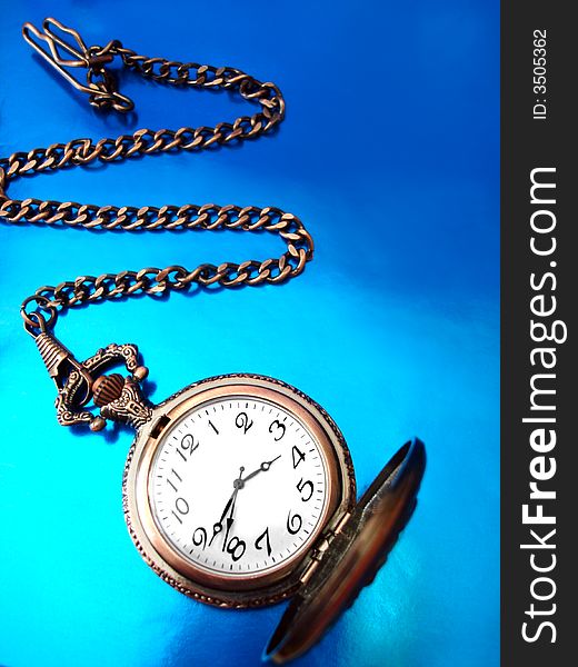 Close-up of old golden clock on blue background