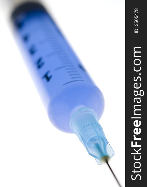 Close-up on white background of a syringe with needle and blue liquide inside. Close-up on white background of a syringe with needle and blue liquide inside.