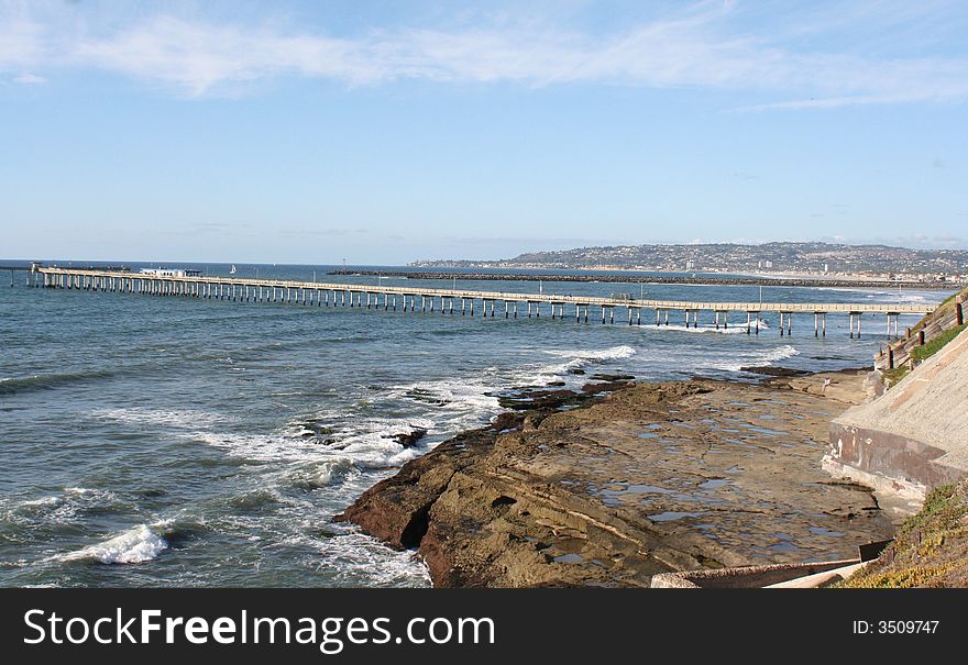 This is a photo of the Ocean Beach Pier, the rocky Pacific Ocean coastline and tidepools and the surf. This is a photo of the Ocean Beach Pier, the rocky Pacific Ocean coastline and tidepools and the surf