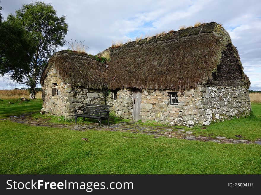 A traditional Scottish farmhouse in a field. The walls are made of stone and the roof is thatched. A traditional Scottish farmhouse in a field. The walls are made of stone and the roof is thatched.