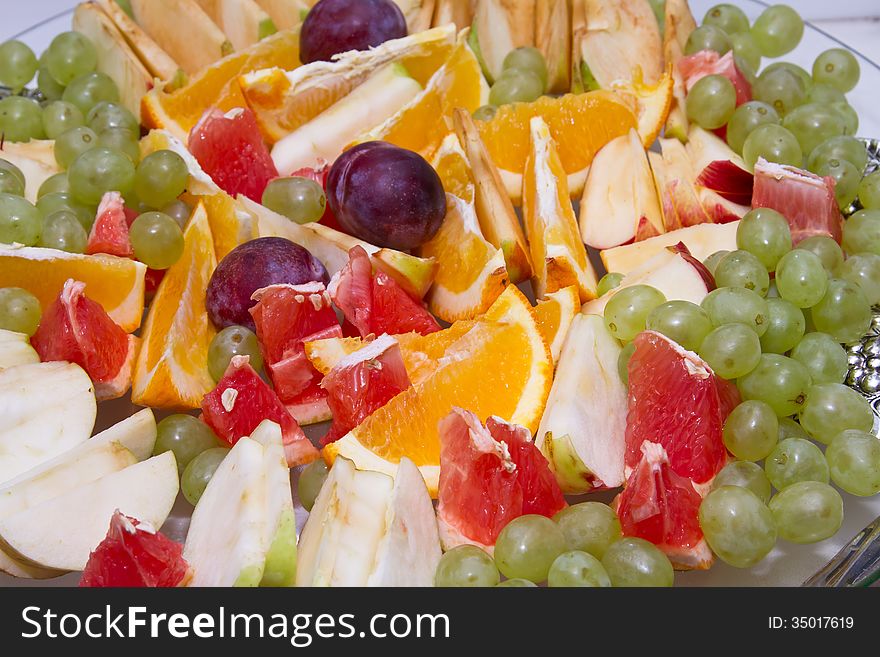 Dish with sliced oranges, grapefruit, Apple and grapes. Dish with sliced oranges, grapefruit, Apple and grapes