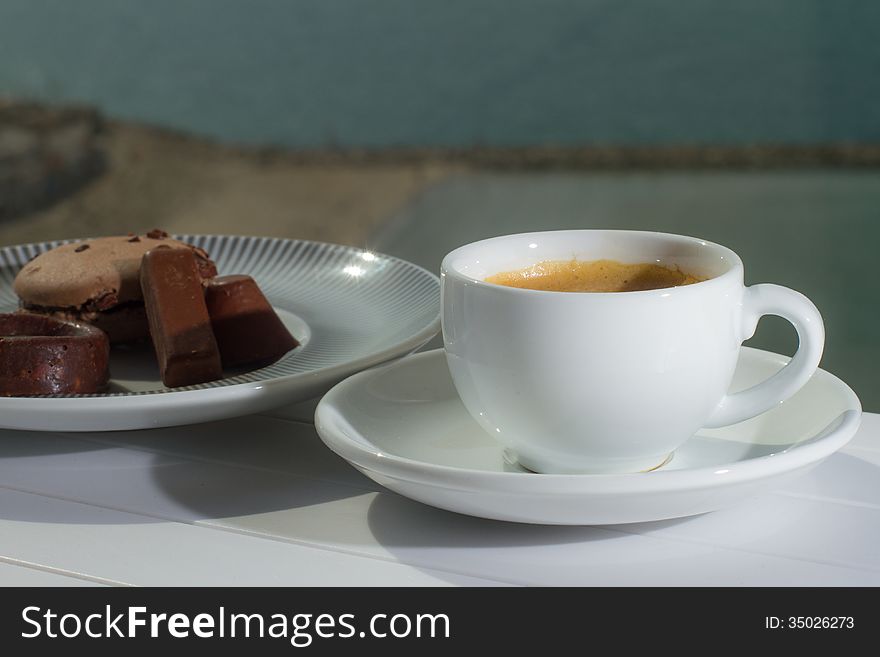 Fresh coffee served with chocolates and cookie. blured background of the beach below. Fresh coffee served with chocolates and cookie. blured background of the beach below