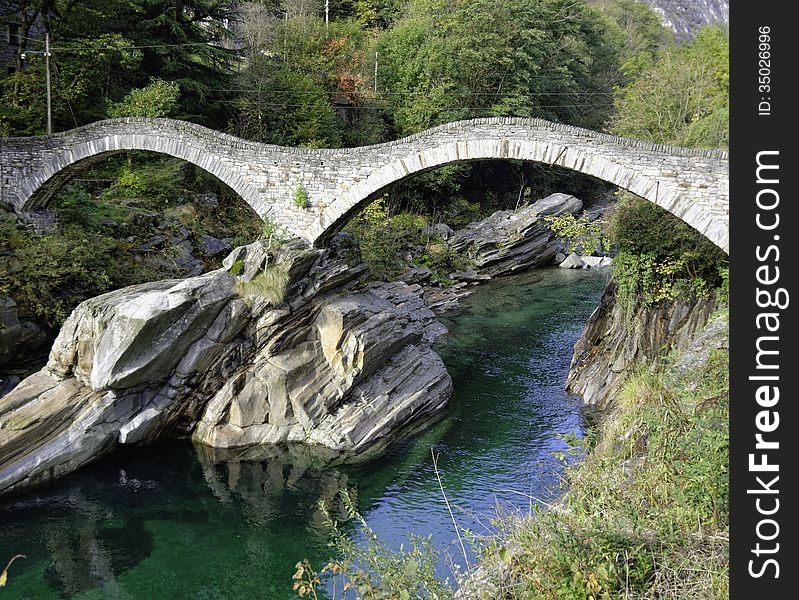 The ancient Ponte dei Salti spans the incredibly green-blue waters of the Verzasca River in the Ticino area of Switzerland. The ancient Ponte dei Salti spans the incredibly green-blue waters of the Verzasca River in the Ticino area of Switzerland.