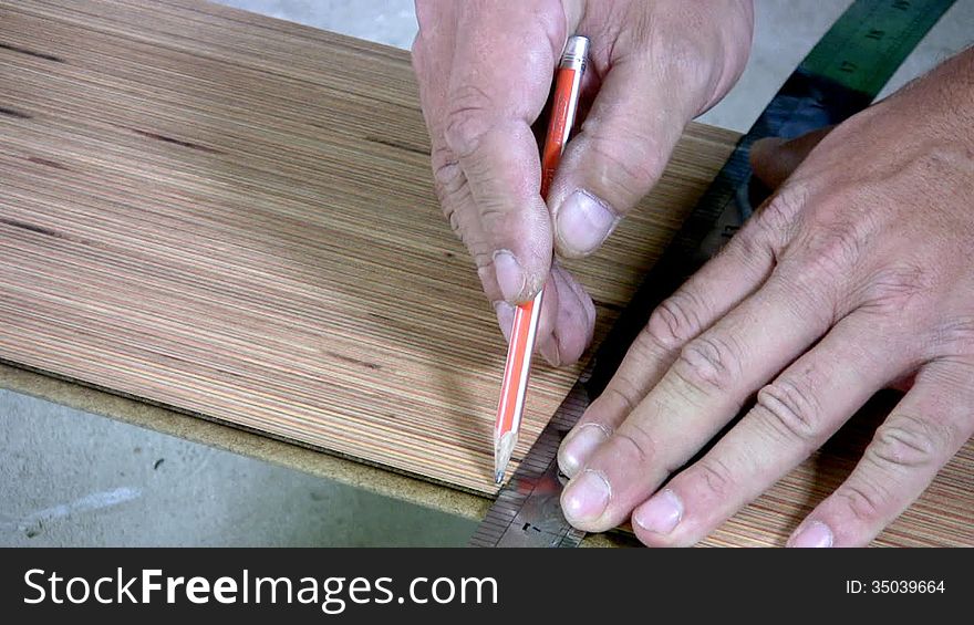 Men's hand draw a pencil line on the laminate. Men's hands are doing sawing with an electric hand-sawing. Men's hand draw a pencil line on the laminate. Men's hands are doing sawing with an electric hand-sawing
