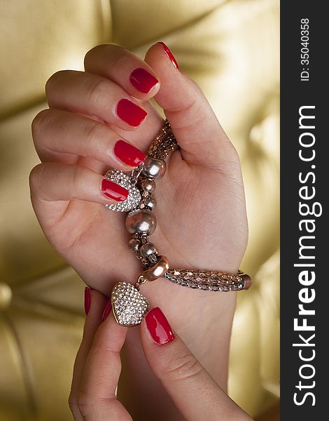 Love two harts on a brecelet in young womans hand with golden background