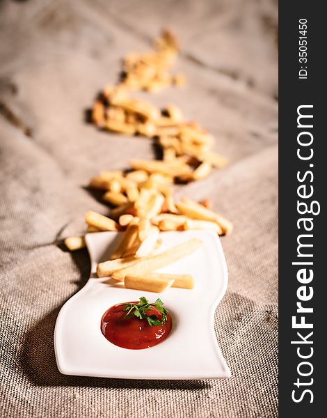 Fried French fries with red sauce ketchup on beautiful plate with linen background. Fried French fries with red sauce ketchup on beautiful plate with linen background