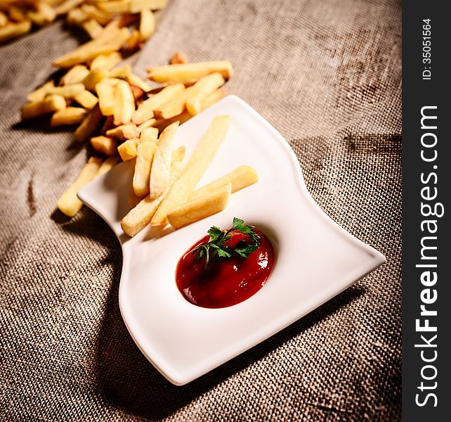 Fried French fries with red sauce ketchup with linen background