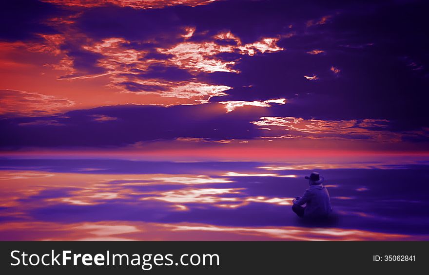 Beautiful sunset sky with clouds reflected in the mirrored surface of the ocean. Pensive cowboy sitting cross-legged and throws small stones. Beautiful sunset sky with clouds reflected in the mirrored surface of the ocean. Pensive cowboy sitting cross-legged and throws small stones