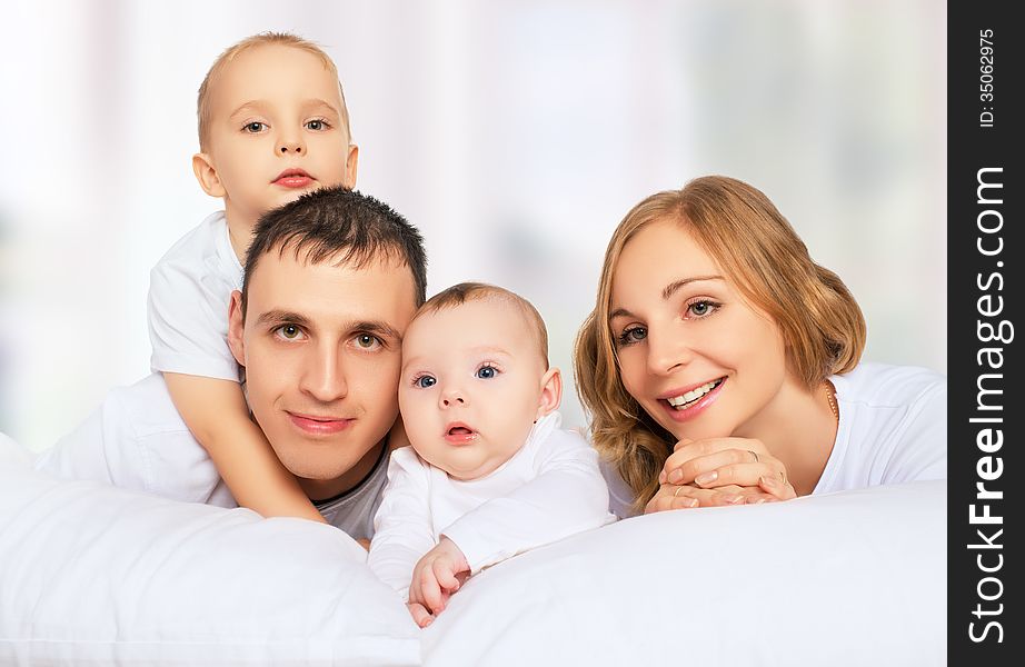 Happy Family Of Father, Mother And Children In White Bed