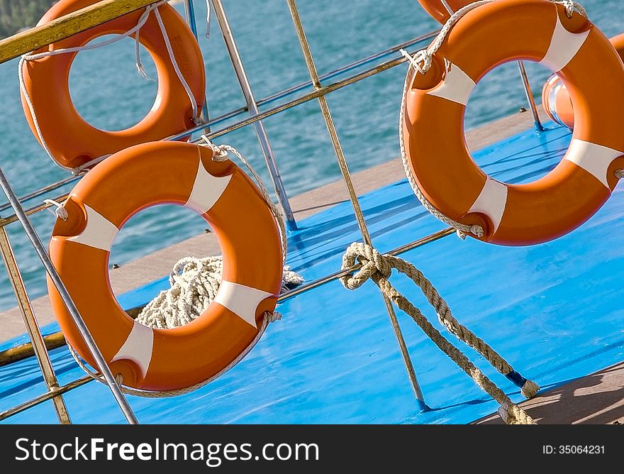 Ship railing and lifebuoy ring. View from the deck of a boat. Sea travel background with lifebuoys. Ship railing and lifebuoy ring. View from the deck of a boat. Sea travel background with lifebuoys.