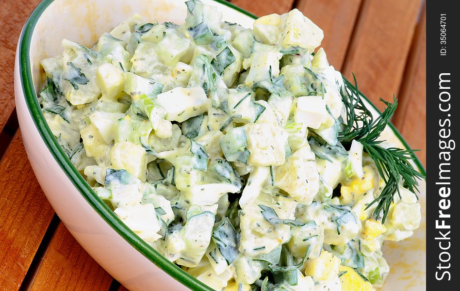 Delicious Freshly Made Creamy Potato Salad in Beige Bowl closeup on Wooden Plank background