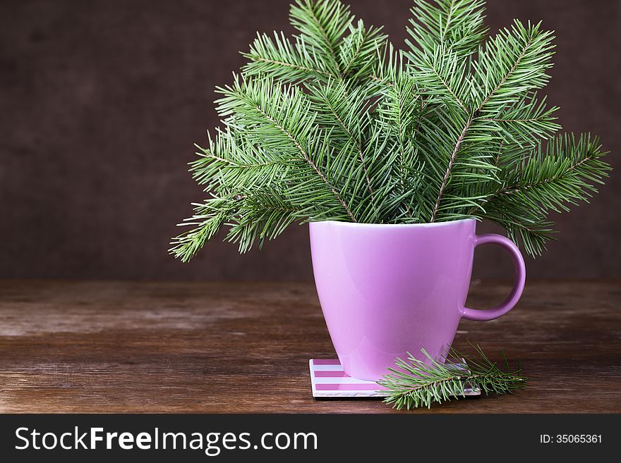 Fir-tree twigs in a mug on old brown wooden table