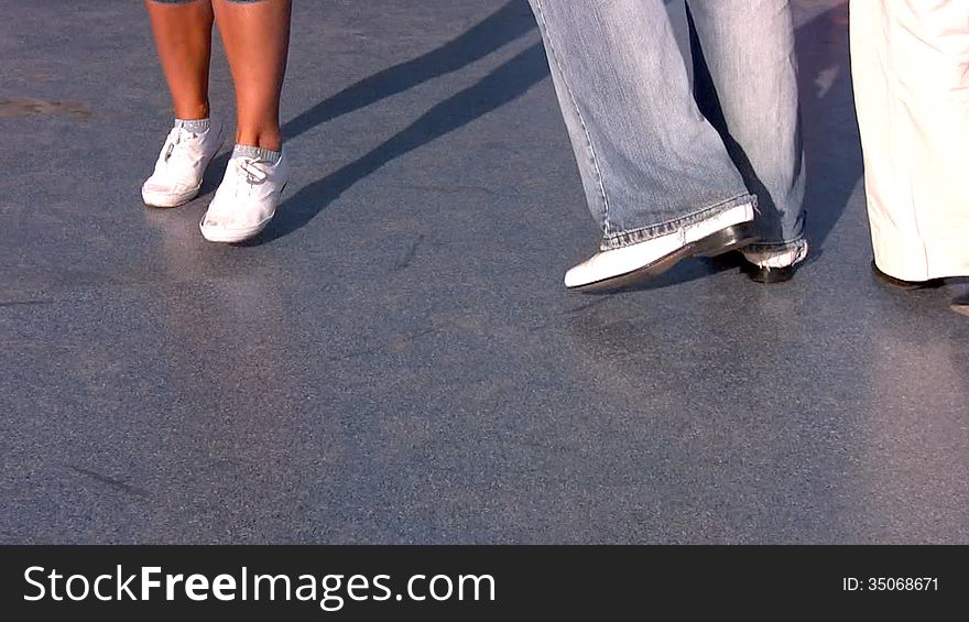 The boy and two girls are dancing on the open jazz scene in the rays of the setting sun. Improvisation. We can see only three pairs of legs. The boy and two girls are dancing on the open jazz scene in the rays of the setting sun. Improvisation. We can see only three pairs of legs