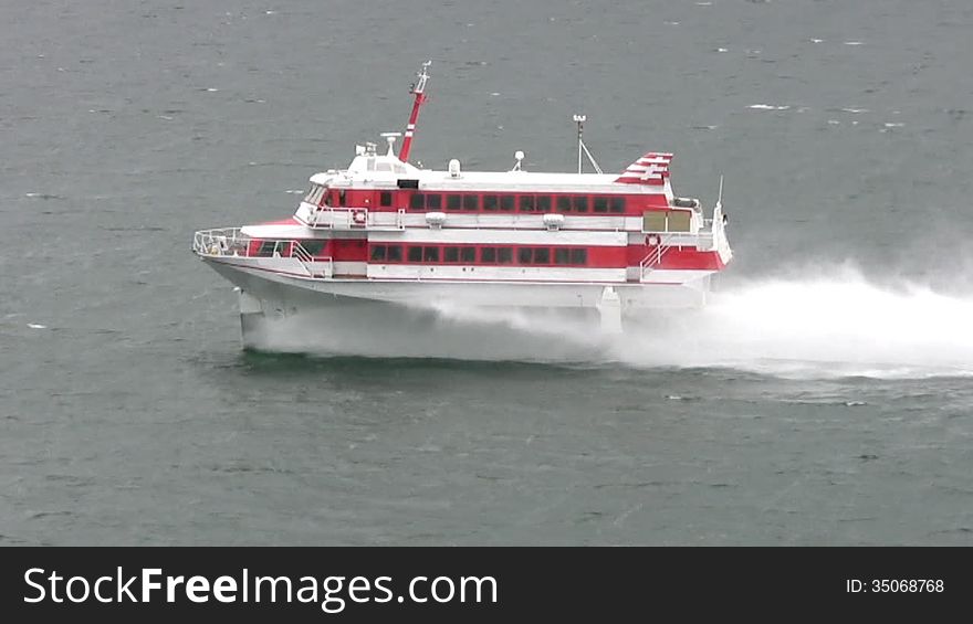 Cloudy weather. On a cold dark sea, swims very fast white boat with red stripes on the hydrofoil. This boat picks up a lot of splashing. Cloudy weather. On a cold dark sea, swims very fast white boat with red stripes on the hydrofoil. This boat picks up a lot of splashing