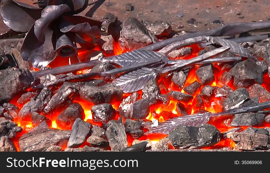 Over the furnace with bright red embers quivering hot air. In the hearth are forged components for metallic flower, and next - finished metal flower. Art of blacksmiths