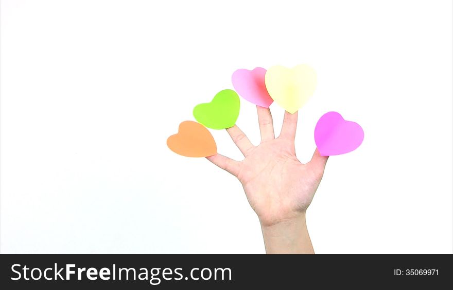 On the fingers of the women's hands are glued five colorful paper labels in the form of hearts. Fingers bend and unbend on a white background. On the fingers of the women's hands are glued five colorful paper labels in the form of hearts. Fingers bend and unbend on a white background