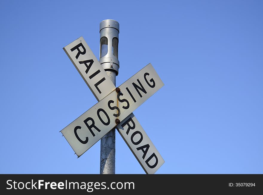 Railroad crossing sign against a clear blue summer sky