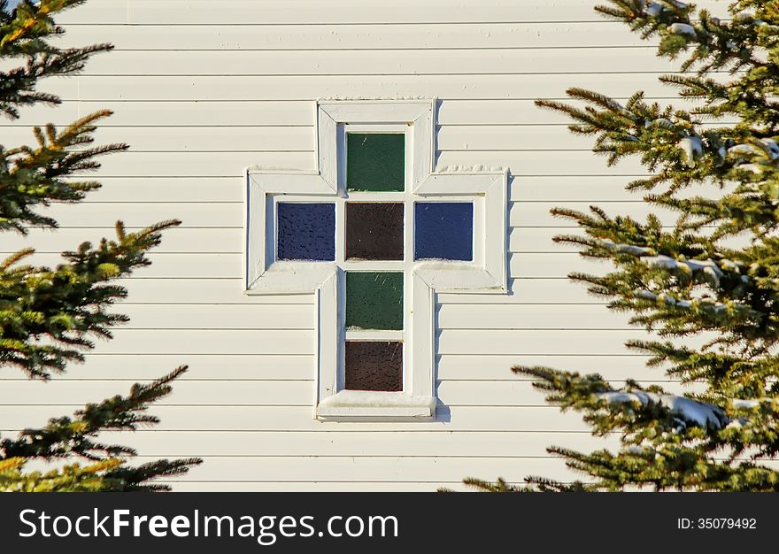 A cross shaped stained glass window. A cross shaped stained glass window