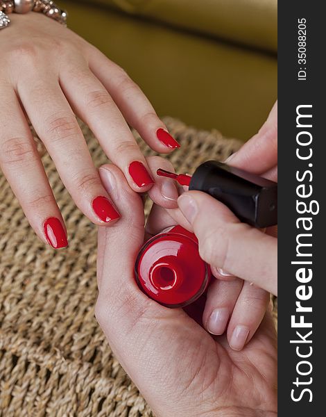Manicure in a cosmetic center adding a red nail polish on her hands with care. Manicure in a cosmetic center adding a red nail polish on her hands with care