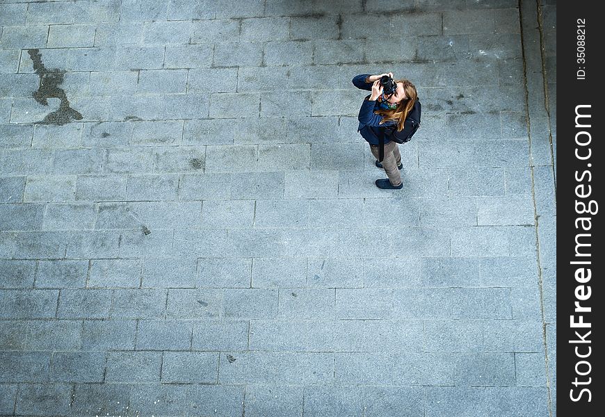 Young woman taking photos on pavement backround