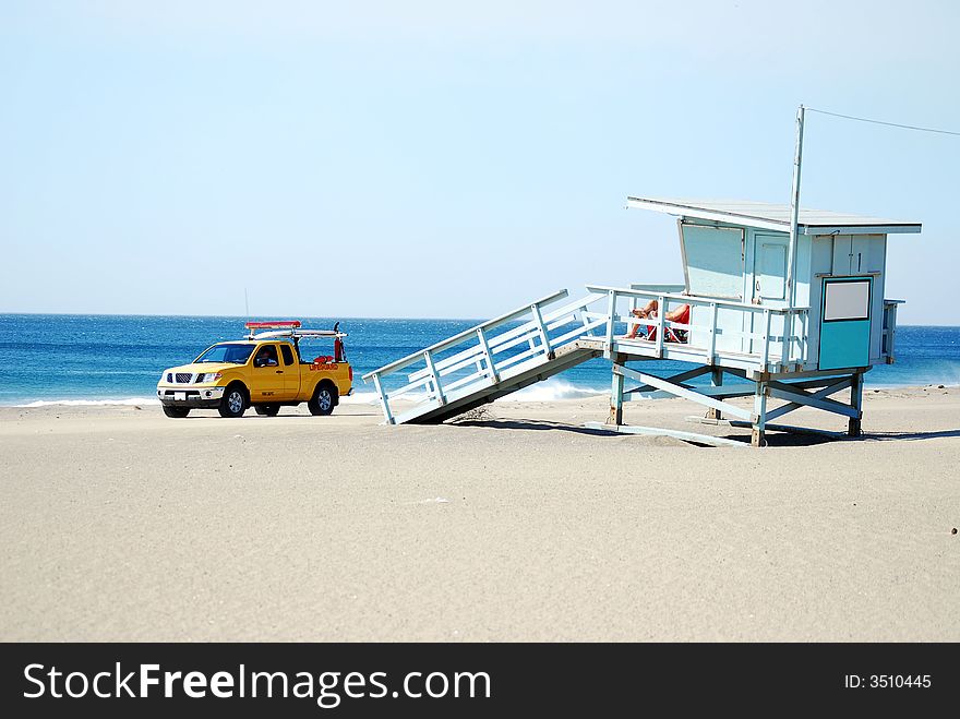 Lifeguard driving truck past lifeguard sitting on lifeguard stand. Lifeguard driving truck past lifeguard sitting on lifeguard stand