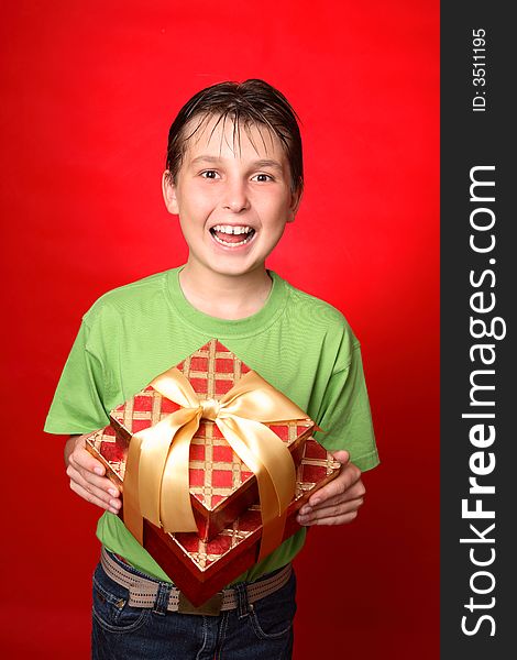 Jovial child holding a red and gold gift tied with gold ribbon. Jovial child holding a red and gold gift tied with gold ribbon.