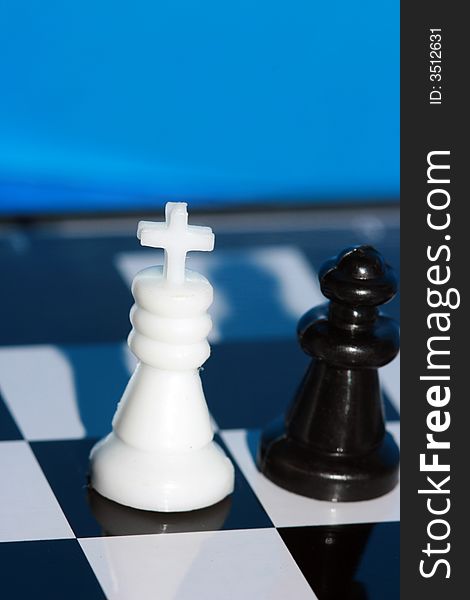 White chess king stands on a chess board with figures