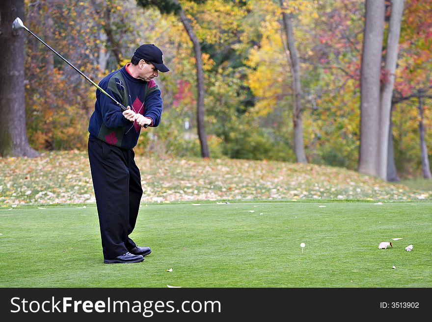 A male golfer plays a game on a beautiful fall day. A male golfer plays a game on a beautiful fall day.