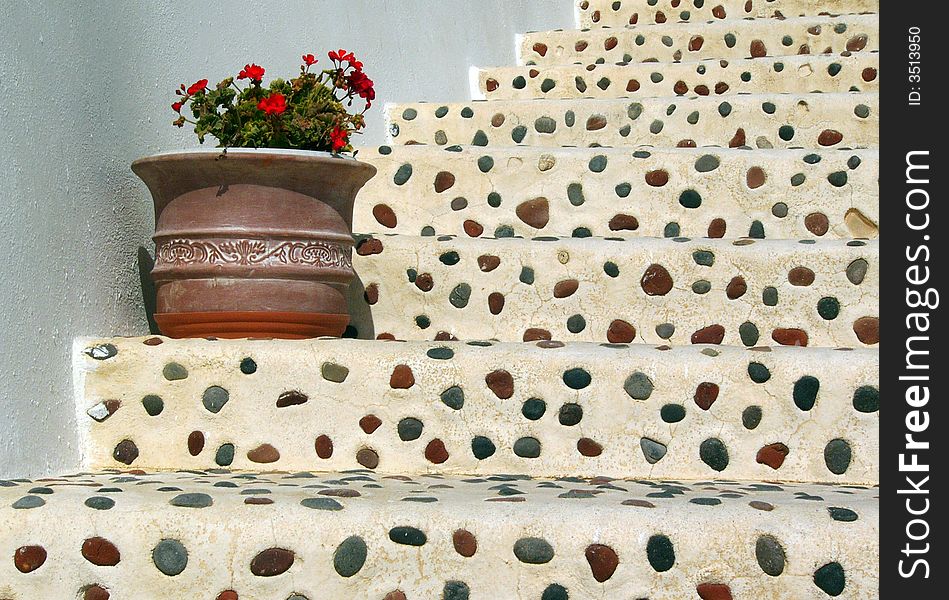 Pebble stairs with flower-pot with pelargonium in Santorini island in Greece