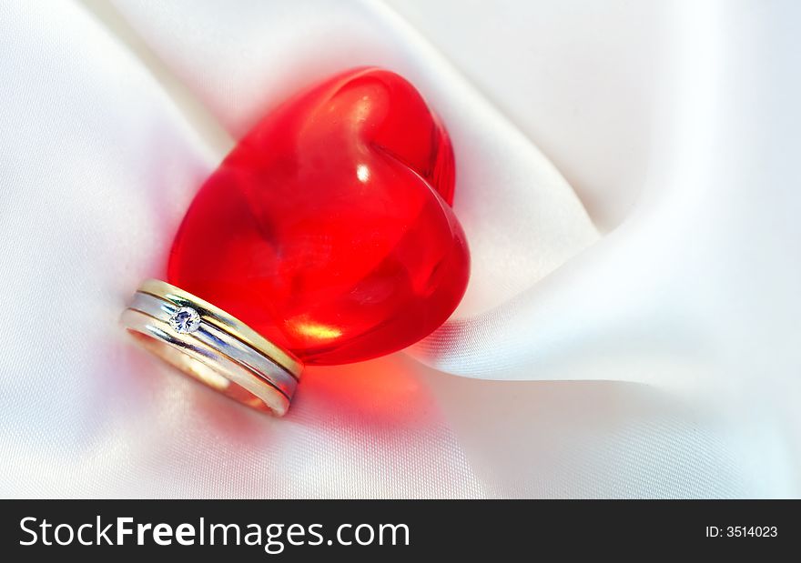 Ring and red heart on satin. Ring and red heart on satin