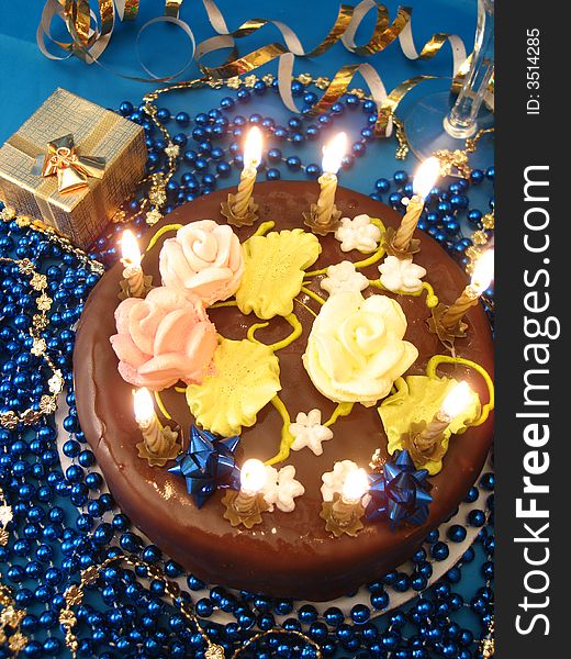 Celebratory table (cake and candles, two glasses with champagne, gift boxes) on blue