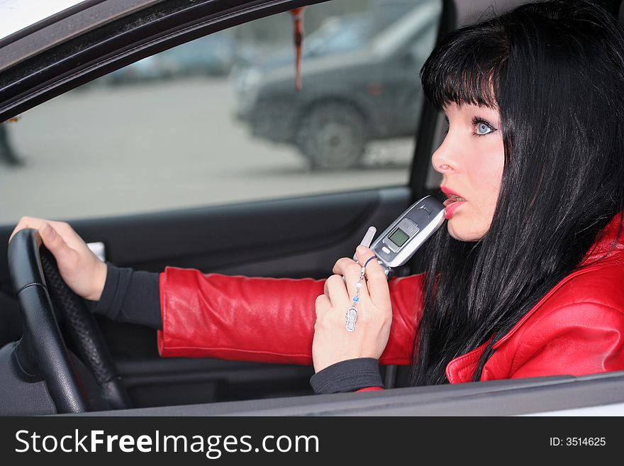Woman in a car is thinking and holding mobile phone