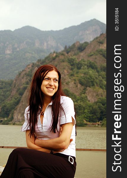 A picture of a smiling brunette girl near the river.