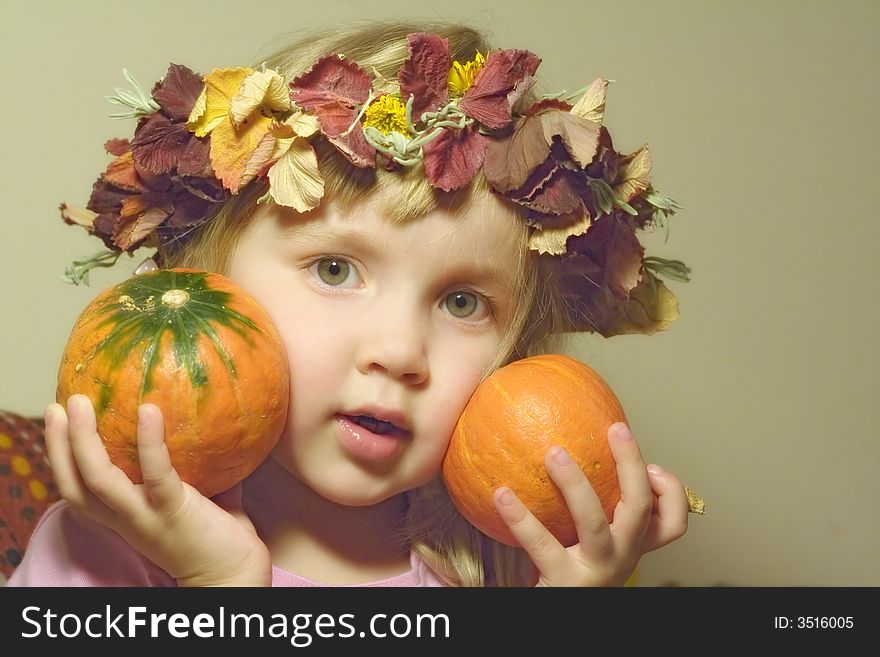 Little girl in diadem from autumn leaves with two little pumpkins in hands. Little girl in diadem from autumn leaves with two little pumpkins in hands