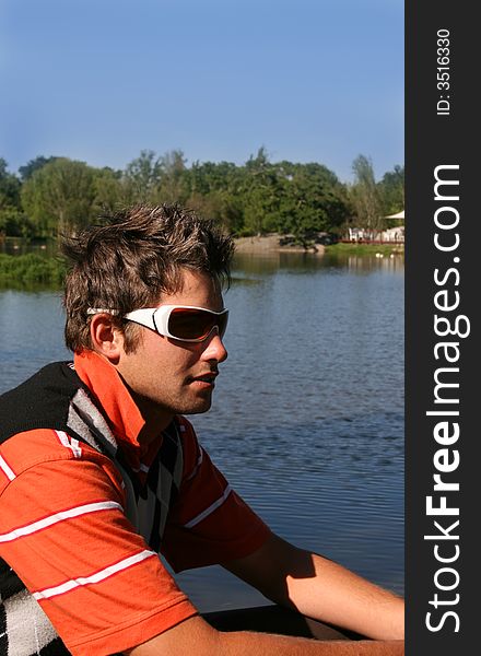 Young man sitting near the edge of a lake. Young man sitting near the edge of a lake