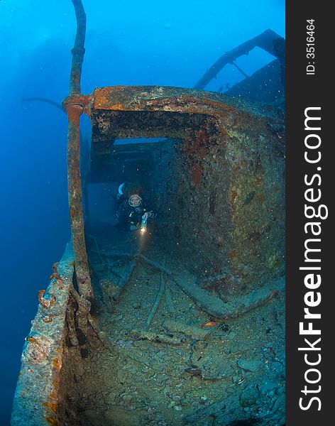 Woman scuba diver exploring the hull of a war ship wreck. Woman scuba diver exploring the hull of a war ship wreck