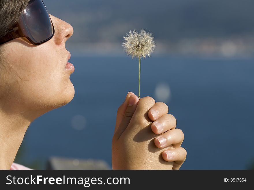 Young woman holding a small dandelion flower. Young woman holding a small dandelion flower