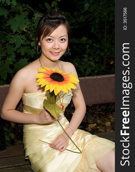 A girl holding a sunflower sitting in chair. A girl holding a sunflower sitting in chair