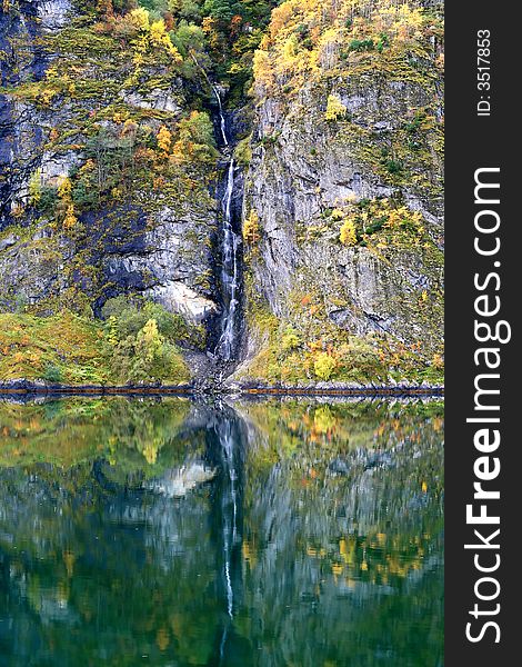 Waterfall in forest with autumn colors - vertical orientation