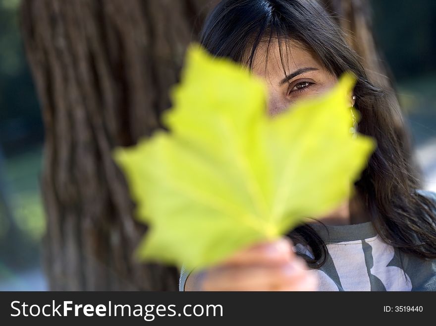 Beautiful young woman holding maple leaf - focus in on the eye