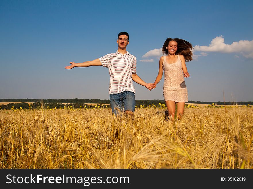 Young Couple Running Through  Wheat Field