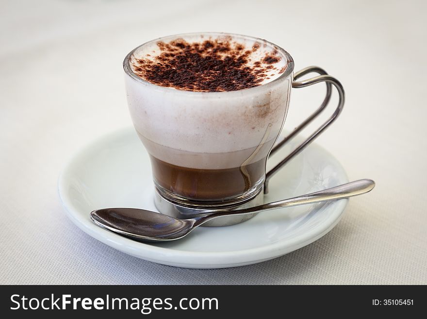 Closeup of brown silky latte coffee drink on white saucer with spoon. Closeup of brown silky latte coffee drink on white saucer with spoon.