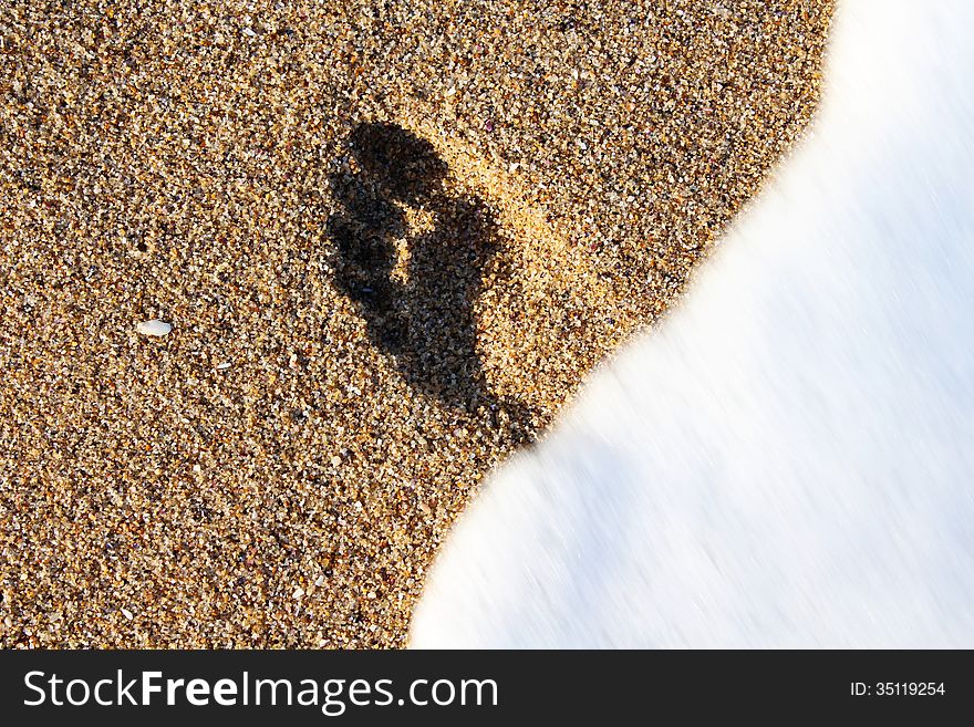 A photo of footprint is washing away by sea foam