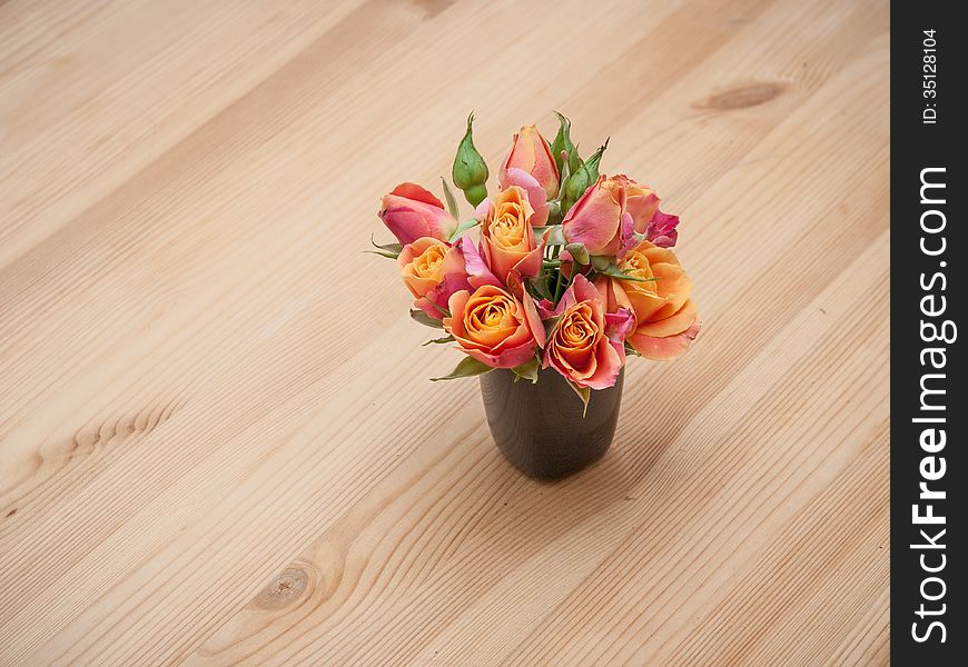 Simple arrangement from orange roses on wooden background