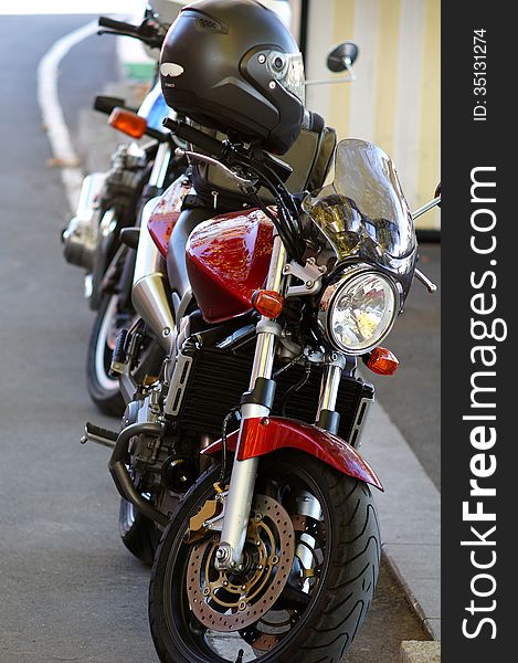 One red and one black motorcycle parked aside the road with helmet. One red and one black motorcycle parked aside the road with helmet