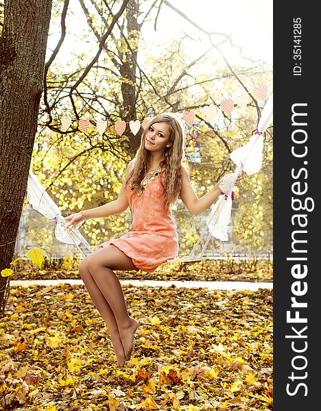 Beautiful Woman Swinging With Autumn Leaves