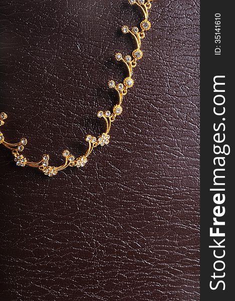 Gold necklace jewellery on textured lether background