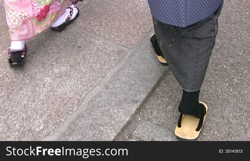 Man and woman in Japanese national dress (kimono) and shoes (zori) walk on the granite pavement. Rear view only legs. Man and woman in Japanese national dress (kimono) and shoes (zori) walk on the granite pavement. Rear view only legs