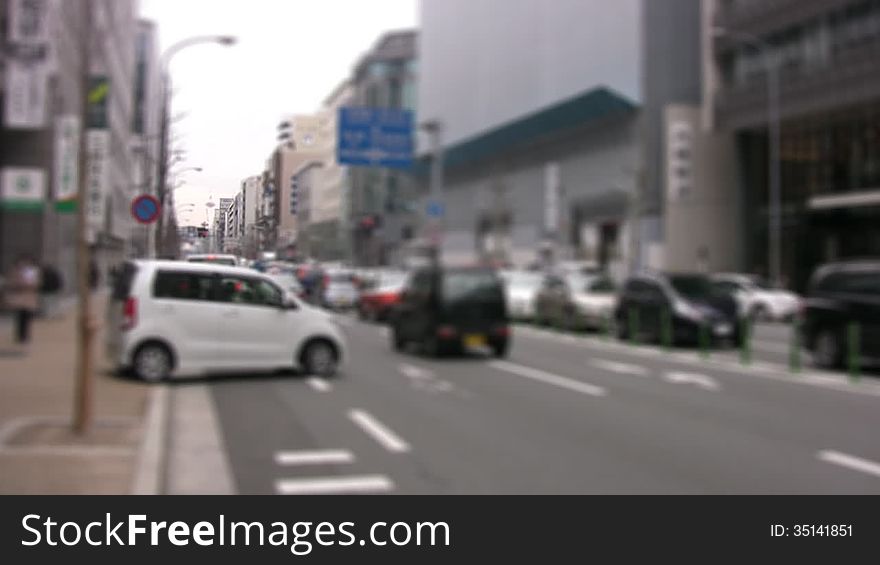 Movement of cars and pedestrians on a city street. The focus at the far end of the street. Slow motion. Movement of cars and pedestrians on a city street. The focus at the far end of the street. Slow motion
